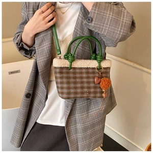Detail of checkered plush bucket bag with faux fur trim and heart charm on a model