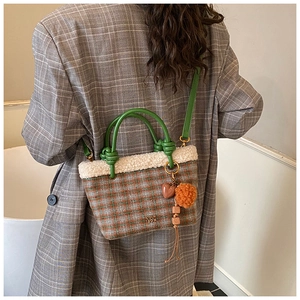 Detail of checkered plush bucket bag with fuzzy trim and green leather knotted handle
