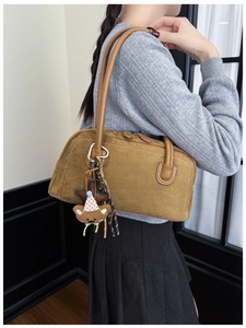 Brown suede underarm bag detail with plush bear charm and sleek silver zipper accents