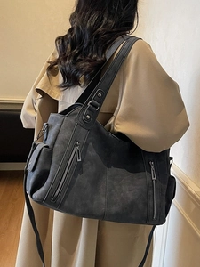 Retro charcoal tote bag with multi-zipper compartments and crossbody strap on a model