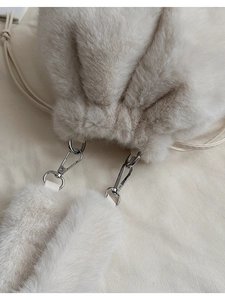 Detailed close-up of fluffy faux fur texture and silver metal clasp on ivory bucket bag