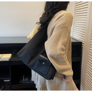 Detailed view of black matte tote bag featuring front pocket with silver snap button closure