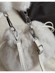 Detail of white faux fur bucket bag featuring drawstring closure and silver metal hardware