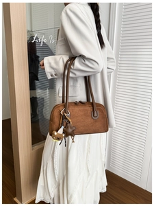 Detail of brown suede Boston bag with star charms worn by model in a minimalist room