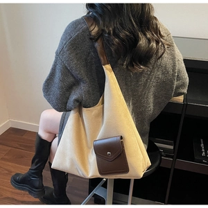 Detail of canvas tote bag featuring brown leather pocket and adjustable shoulder strap