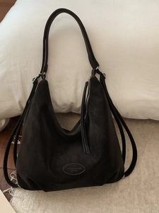 Black large capacity minimalist tote bag resting on white pillow and cozy carpet