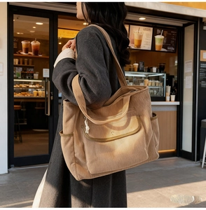 Detail of camel corduroy tote bag showing front flap pocket and ribbed texture on shoulder