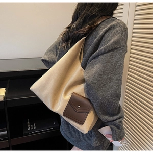 Detail view of the canvas tote bag with a brown leather pocket and metal buckle clasp