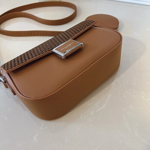 Detail of a brown crossbody bag with houndstooth flap and round coin purse attachment