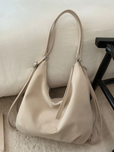Minimalist cream leather tote bag with large capacity and embossed logo on a soft background