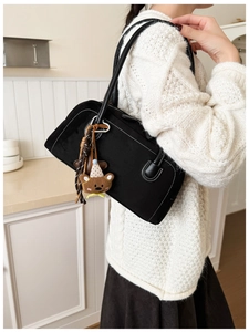 Detail of black suede hobo bag with white stitching and cute bear charm pendant