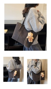 Dettaglio della grande borsa tote in pelle scamosciata marrone scuro con ciondolo a orso