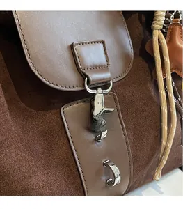 Detail of brown suede tote bag featuring silver metal clasp and star charm pendant