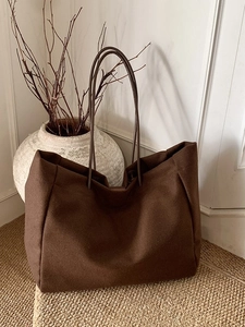 Minimalist brown wool tote bag with slim straps in a calm interior setting