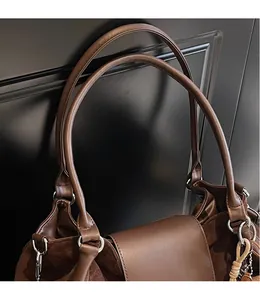 Detail of dark brown tote bag showing slim shoulder straps and contrast suede texture