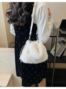 Detail of white plush faux fur bucket bag featuring adjustable leather shoulder strap