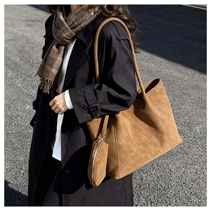 Close-up of brown suede tote bag with textured stitching and a matching round pouch