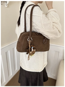 Detail view of brown suede underarm bag with a cute bear keychain charm on shoulder strap