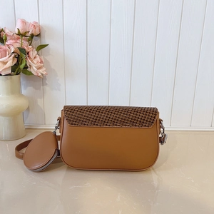 Detailed view of brown woven saddle bag with matching round coin purse on a white wood surface