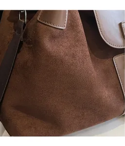 Close-up of brown suede tote bag featuring smooth leather trim and premium stitching detail