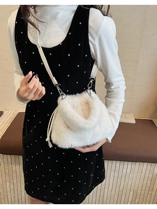 Close-up of cream faux fur bucket bag with silver metal hooks and drawstring detail