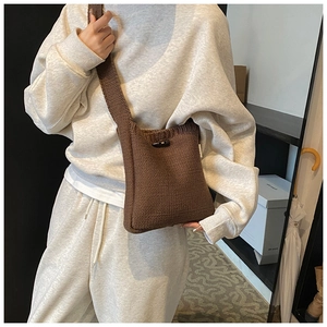 Detail of hand-knitted brown crossbody bag with horn buckle and thick knit texture