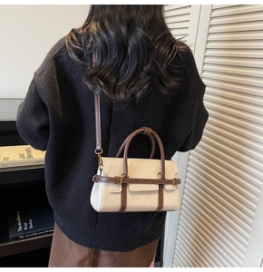 Detail of minimalist cream and brown leather crossbody bag styled on a model's shoulder