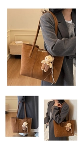 Dettaglio di una borsa tote in pelle scamosciata marrone con cuciture e ciondolo a orsetto