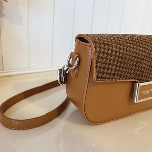 Detail view of woven leather crossbody bag with silver buckle and caramel brown stitching