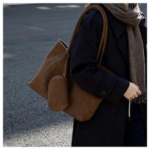 Close-up of brown suede tote bag featuring a matching coin purse and decorative stitching
