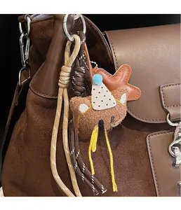 Close-up of cute brown plush bear charm with party hat on a suede tote bag