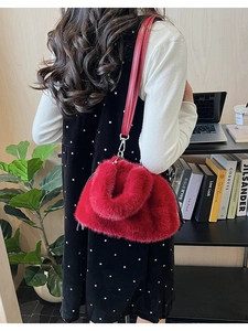 Furry red plush bucket bag with leather strap styled in a modern home office setting