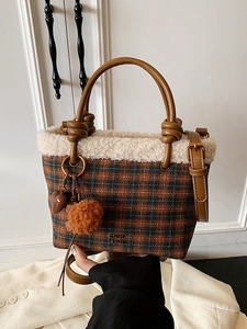 Brown plaid plush bucket bag with white faux fur trim and heart charm handheld by model