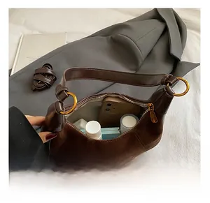 Dettaglio della borsa sottobraccio in pelle scamosciata marrone con capacità interna