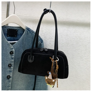 Detail of black suede bag with white stitching, dual zippers and cute bear charm