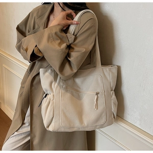 Detail of off-white corduroy tote bag showing front zipper pocket and side pockets
