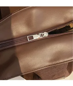Macro detail of polished silver metal zipper on dark brown leather crossbody bag