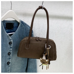 Detail of a brown suede underarm bag featuring a cute bear charm and double zipper design