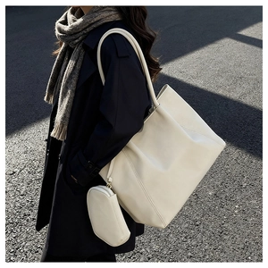 Detail of a white large tote bag with matching pouch shown in outdoor sunlight
