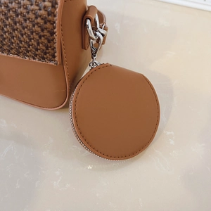 Detail of brown leather crossbody bag with woven texture lid and a mini coin purse