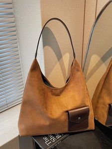Brown matte suede tote bag with leather strap and pocket in a minimalist indoor setting