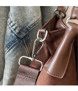 Close-up of brown suede bag featuring premium silver hardware hooks and textile strap