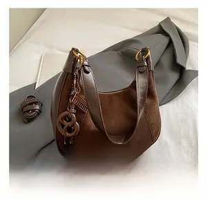 Dettaglio borsa hobo in pelle scamosciata marrone con fibbie dorate e ciondolo retrò