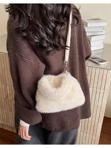Detail of soft cream faux fur bucket bag with slender shoulder strap and silver metal buckle