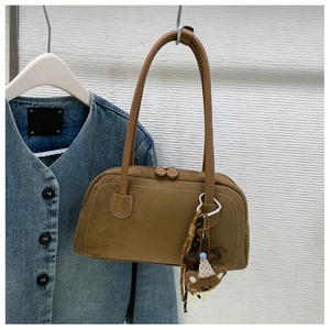 Macro detail of brown suede underarm bag texture with cute teddy bear charm pendant