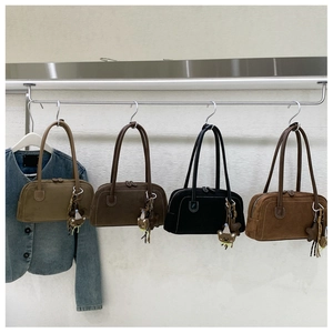 Row of velvet shoulder bags in khaki, brown, black with cute bear charms on a rack