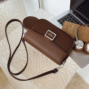 Detailed shot of a brown leather crossbody bag with metal buckle and mini coin purse charm