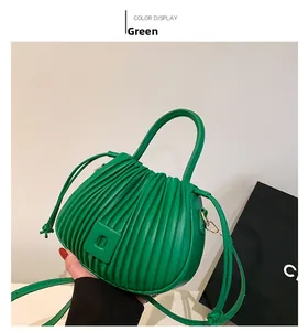 Détail d'un sac à main vert en cuir PU plissé avec texture accordéon et poignée rigide