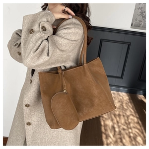 Brown suede tote bag with matching small pouch shown on person in oat coat