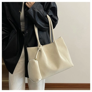 Detail of a large off-white tote bag with V-shaped stitching and a small zipper pouch